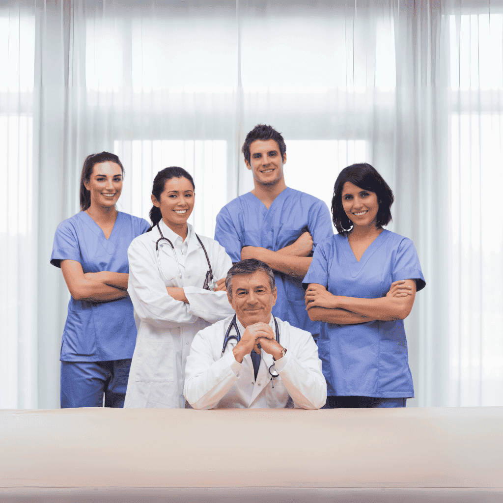 Grupo de profesionales de la salud con uniforme médico azul y bata blanca posando en un entorno clínico moderno.