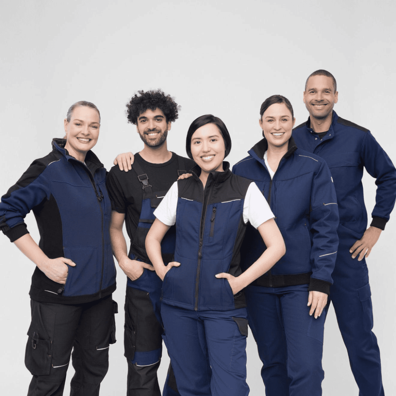 Equipo de trabajadores usando uniforme operativo azul y negro en fondo blanco, mostrando ropa de dotación industrial.
